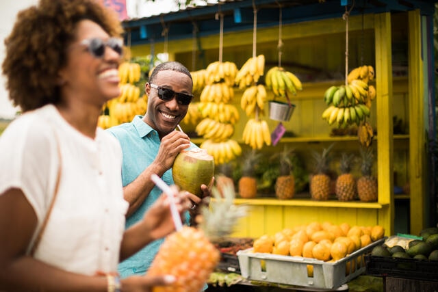 Couple laughing and drinking from fresh pineapples at fruit stand, Big Island, Hawaii.