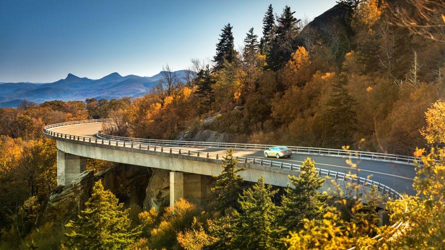 Stunning image, Blue Ridge Parkway curve, fall foliage, blue sky, Grand Father Mountain, North Carolina.