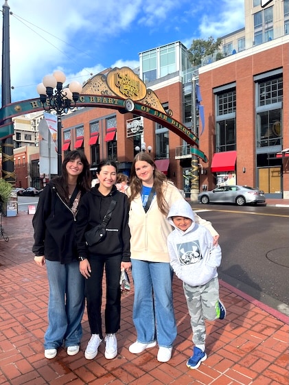 Teenage family and friends standing on red brick sidewalk in front of the sign to Gaslamp Quarter in San Diego.